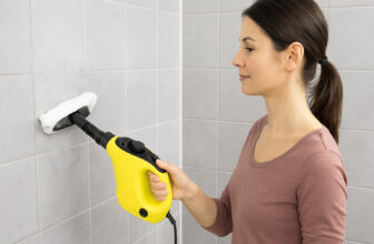 Жена държи жълта ръчна парочистачка, която изкарва пара и почиства плочки в баня