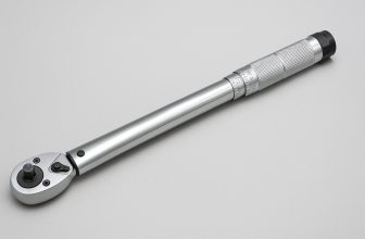 Хромиран динамометричен ключ с релефна дръжка и въртяща се глава, поставен диагонално върху светлосив фон.