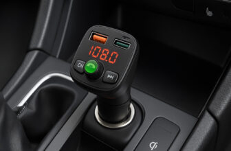 Черен Bluetooth FM трансмитер с LED дисплей и USB портове, включен в 12V гнездо на автомобилен подлакътник.