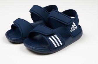 ъмносини детски сандали Adidas с велкро закопчаване и бели декоративни ленти, заснети на бял фон.