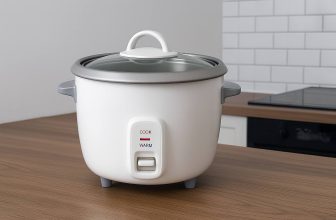 Оризоварка върху дървен кухненски плот с бели плочки и черна печка в модерна кухня.